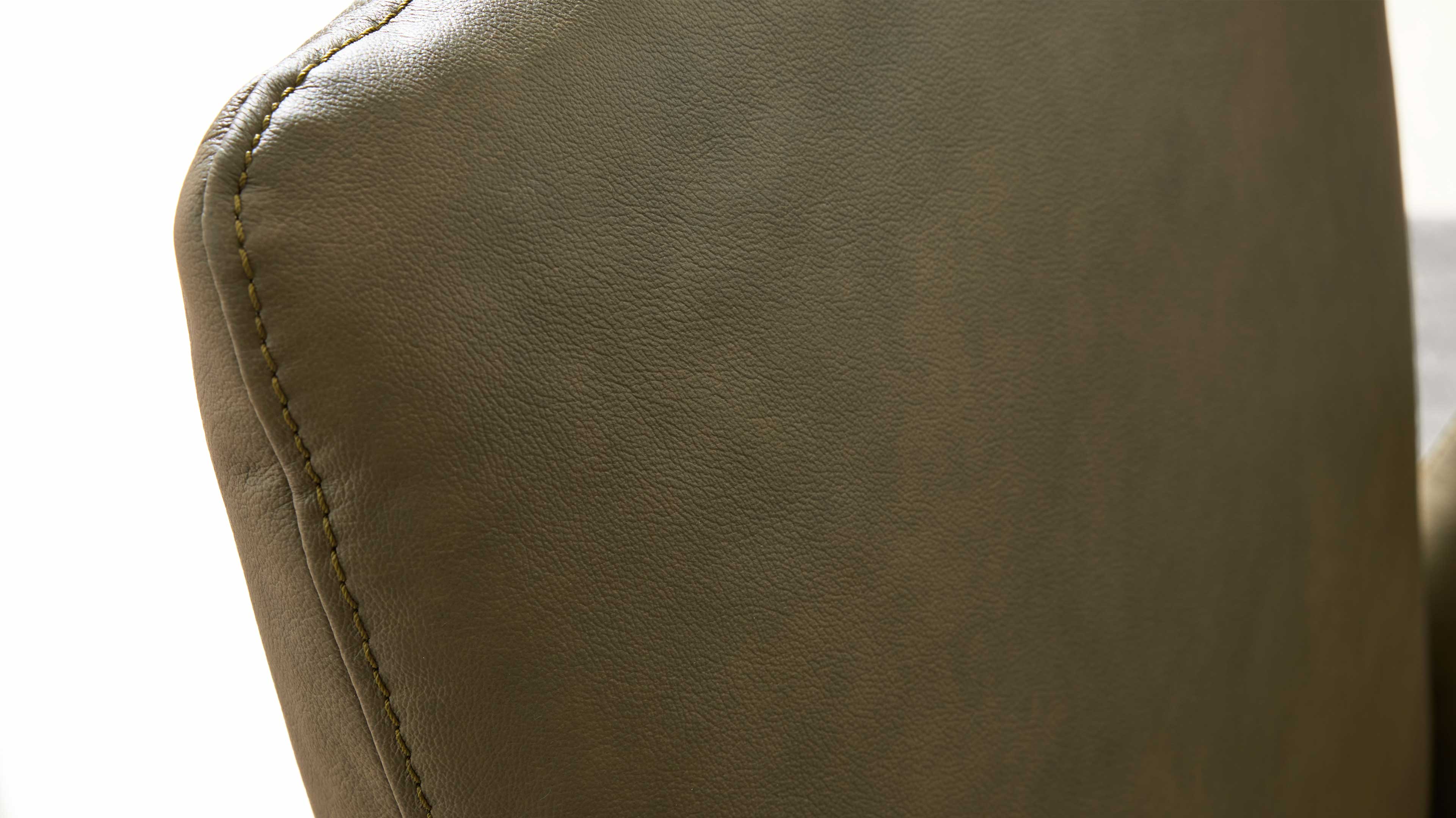 Rückenlehne eines olivgrünen Lederstuhls, sichtbare feine Narbung und seitliche Naht mit kontrastierender, hellerer Steppnaht.